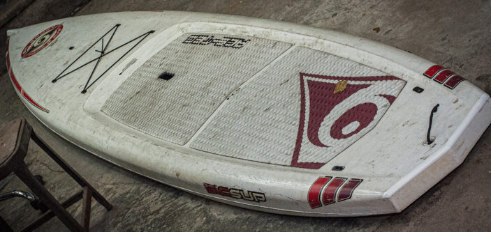 a very used dirty paddlebaord